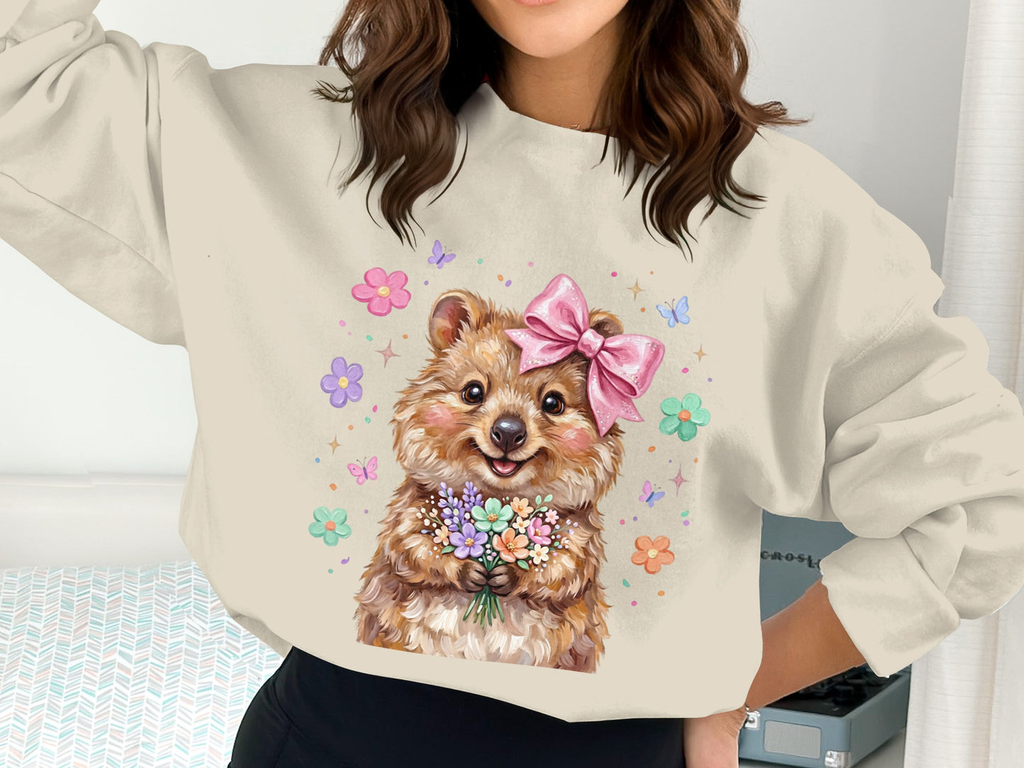 Quokka with pink bow holding bouquet surrounded by flowers and butterflies.