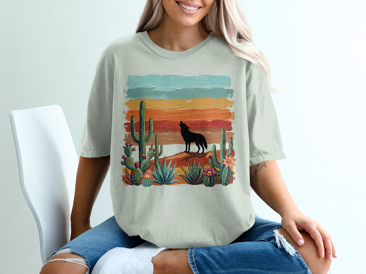 T-shirt with howling wolf silhouette and desert cacti under colorful striped sky.