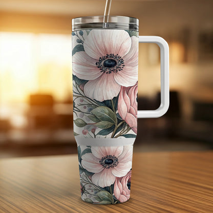 Tumbler with pink floral pattern and handle on a wooden surface.