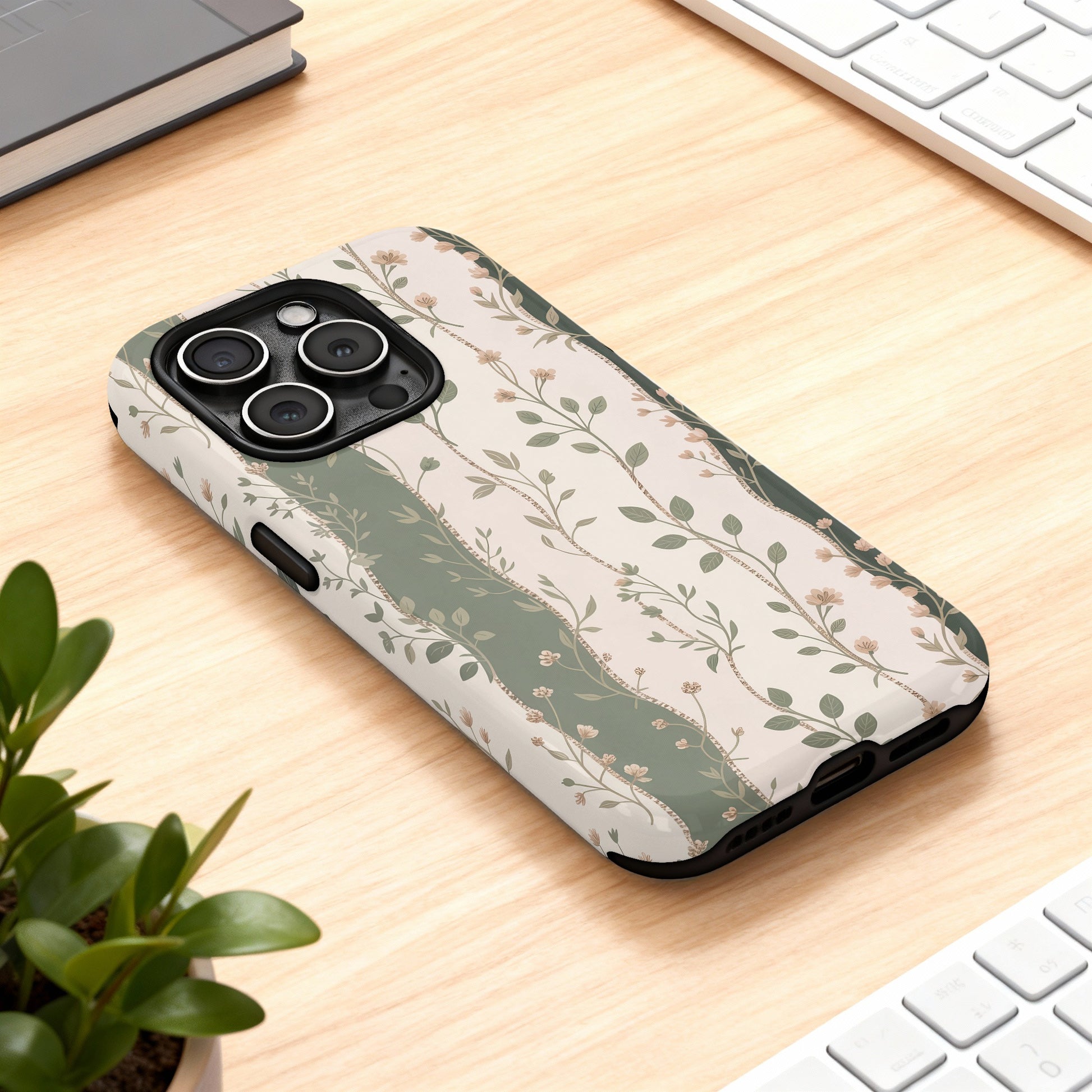 iPhone case with floral and striped green pattern on wooden desk.