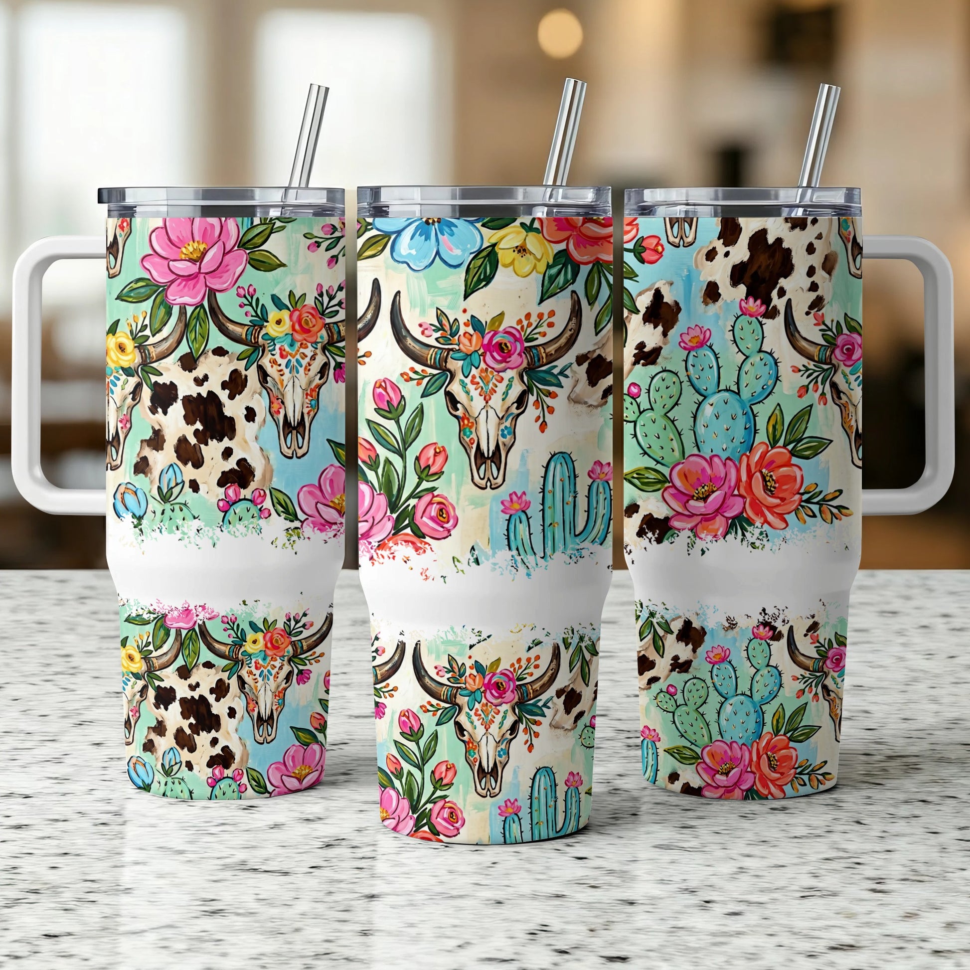 Three tumblers with floral skulls, cacti, and cow print designs.