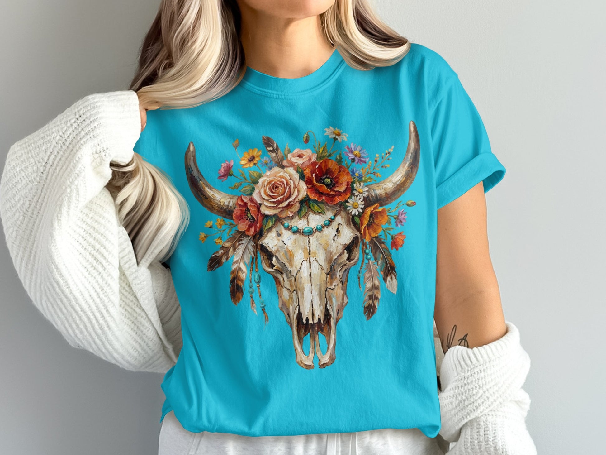 Turquoise t-shirt with a bull skull adorned with flowers and feathers.