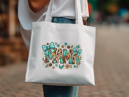 White tote bag with "MAMA" in leopard print, turquoise bows, and floral accents.