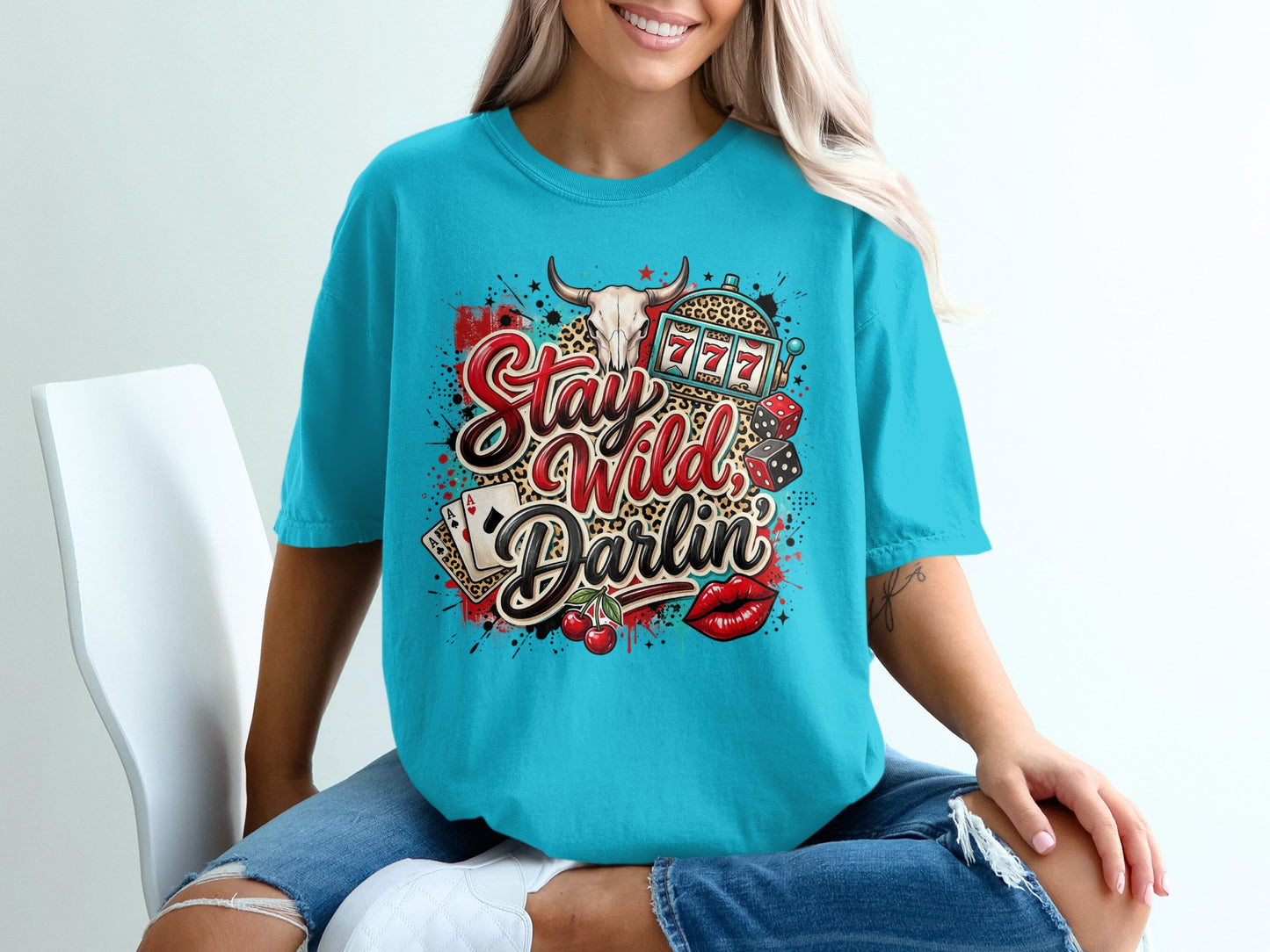 Turquoise t-shirt with "Stay Wild Darlin'" text, slot machine, dice, cards, cherries, and lips.