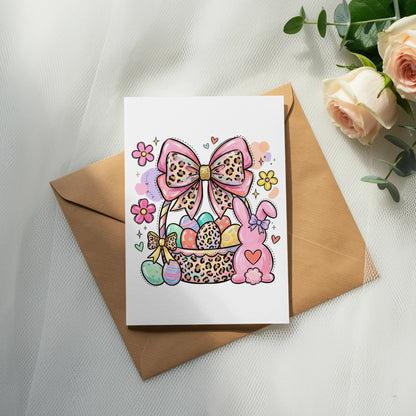 Easter card with bunny, basket of eggs, and bow on brown envelope.