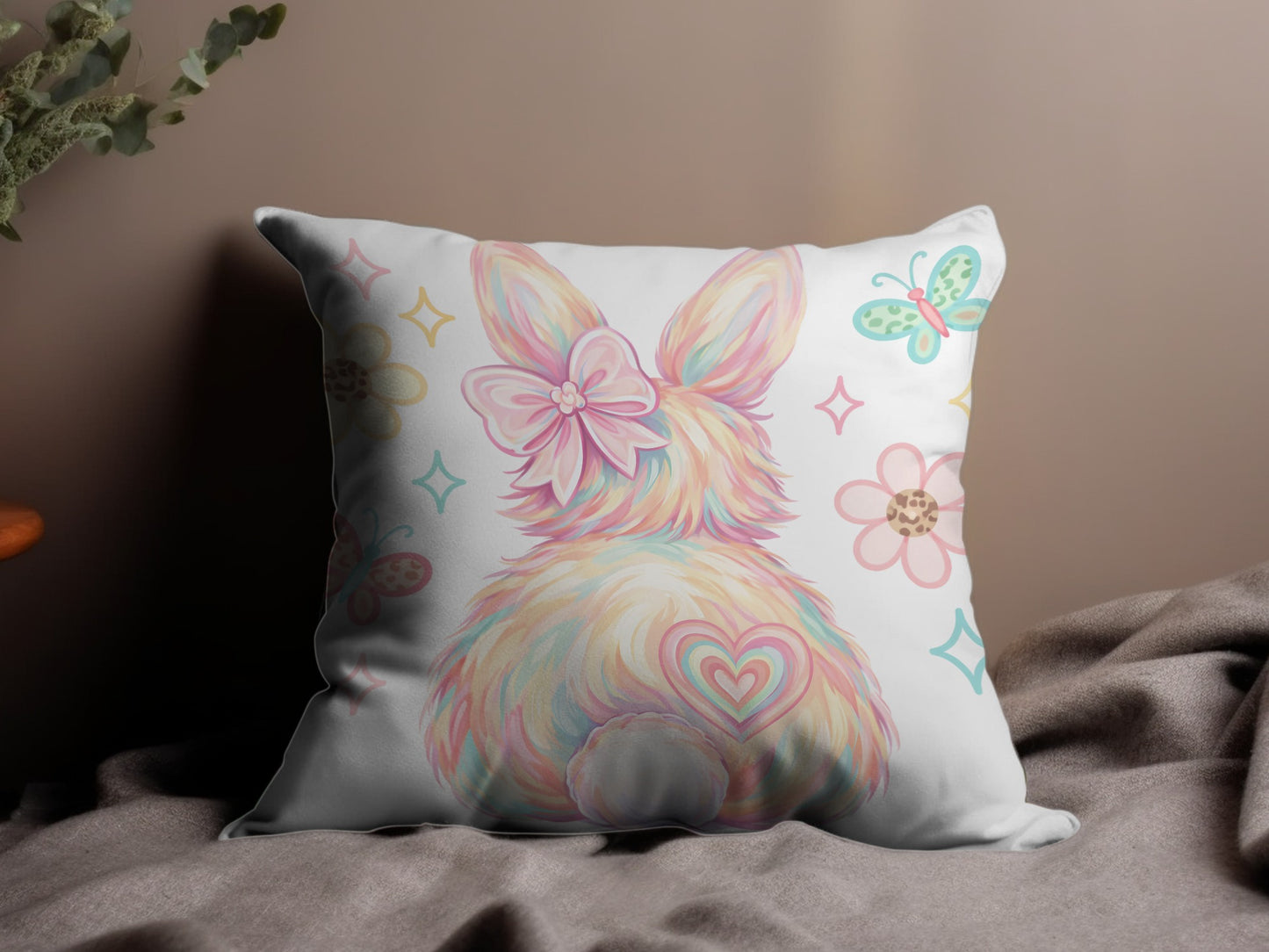 Fluffy pastel bunny with bow and heart tail on decorative pillow.