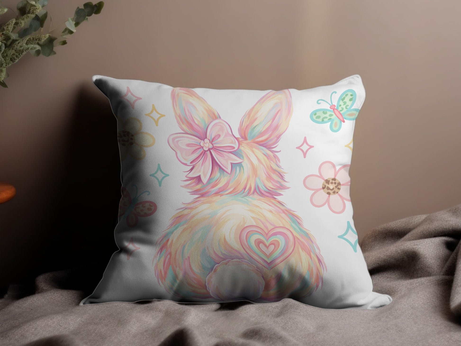 Fluffy pastel bunny with bow and heart tail on decorative pillow.