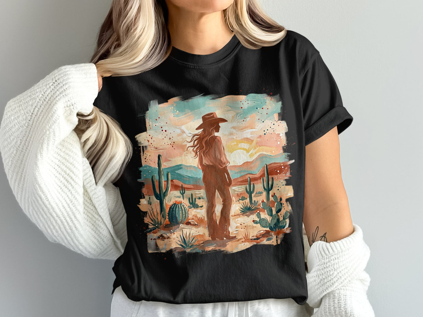 Woman in cowboy hat and Western desert scene graphic on black t-shirt.