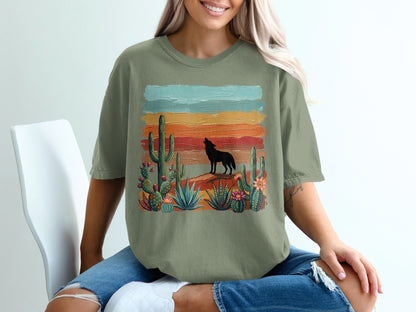 Woman wearing olive green t-shirt with desert wolf and cactus graphic.