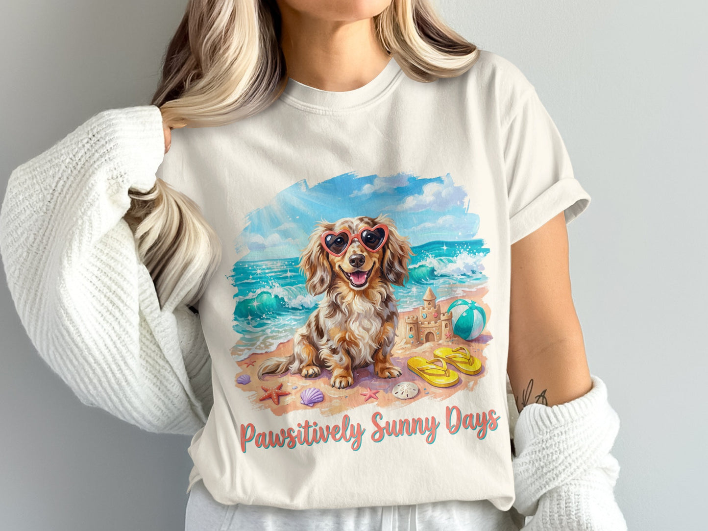 Dachshund wearing heart sunglasses on a beach, with a sandcastle and beach ball.