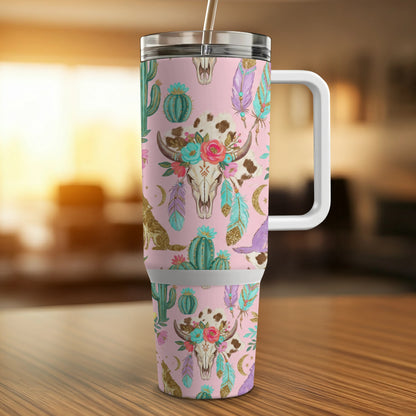 Pink tumbler with cow skull, cactus, and feather design.