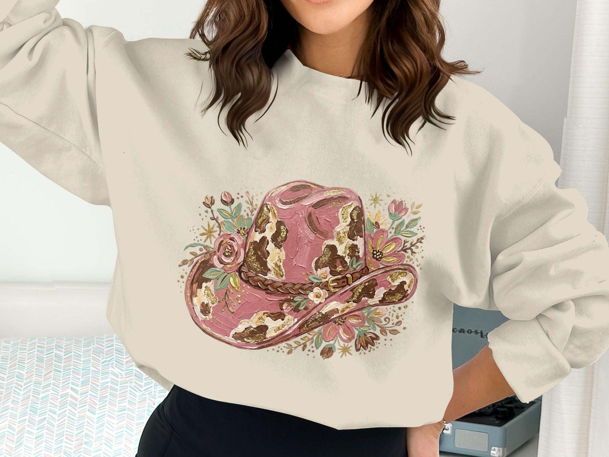 Pink cowboy hat with floral accents on a cream sweatshirt.