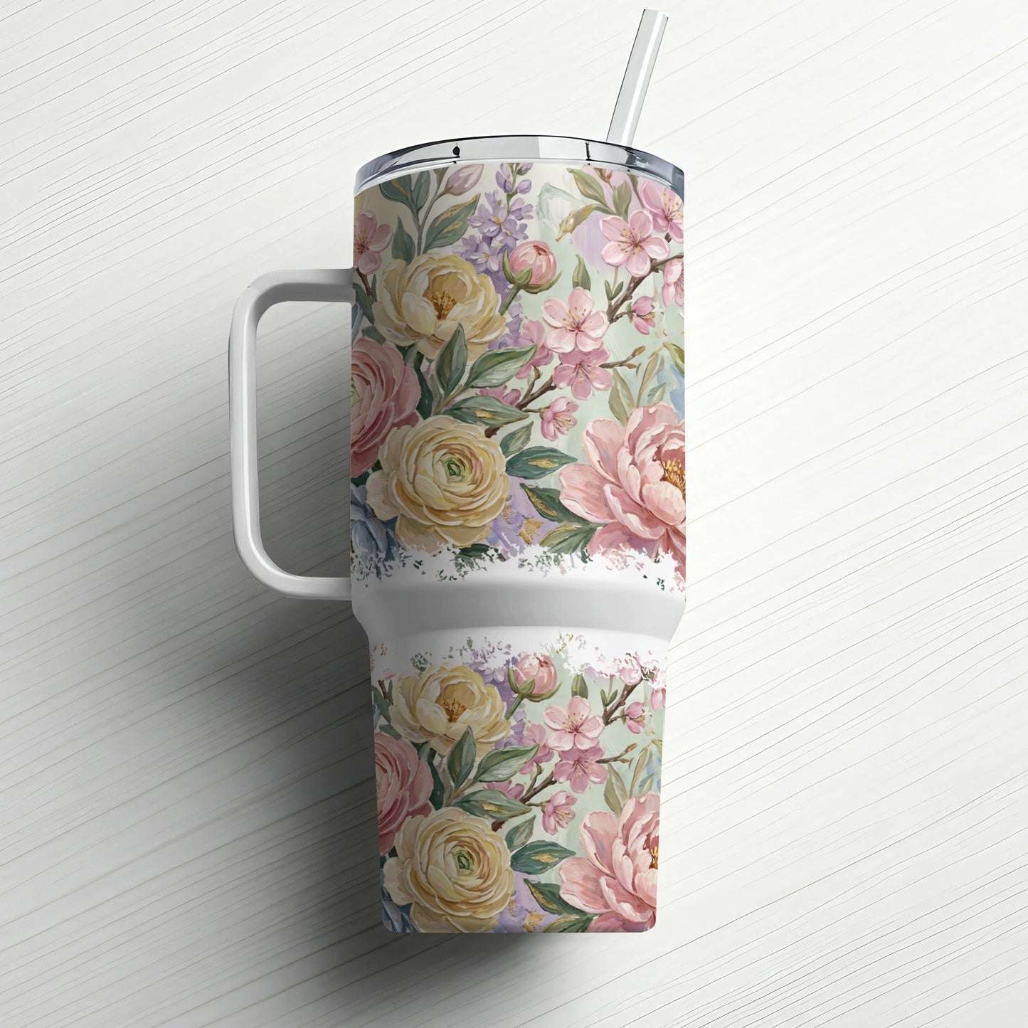 Floral patterned tumbler with a handle and straw, set on a white background.