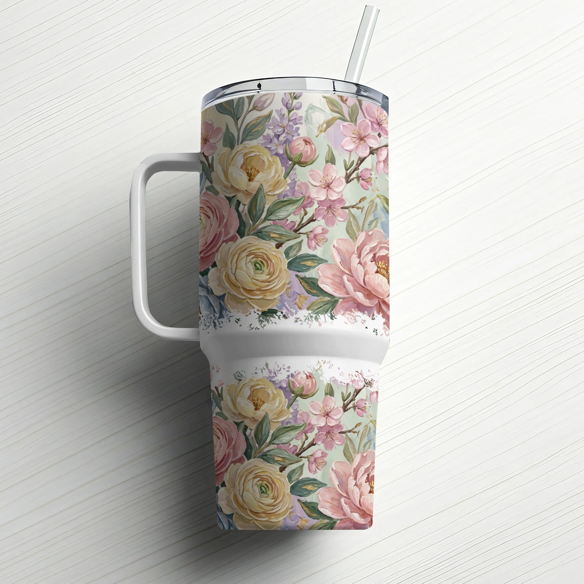 Floral patterned tumbler with a handle and straw, set on a white background.
