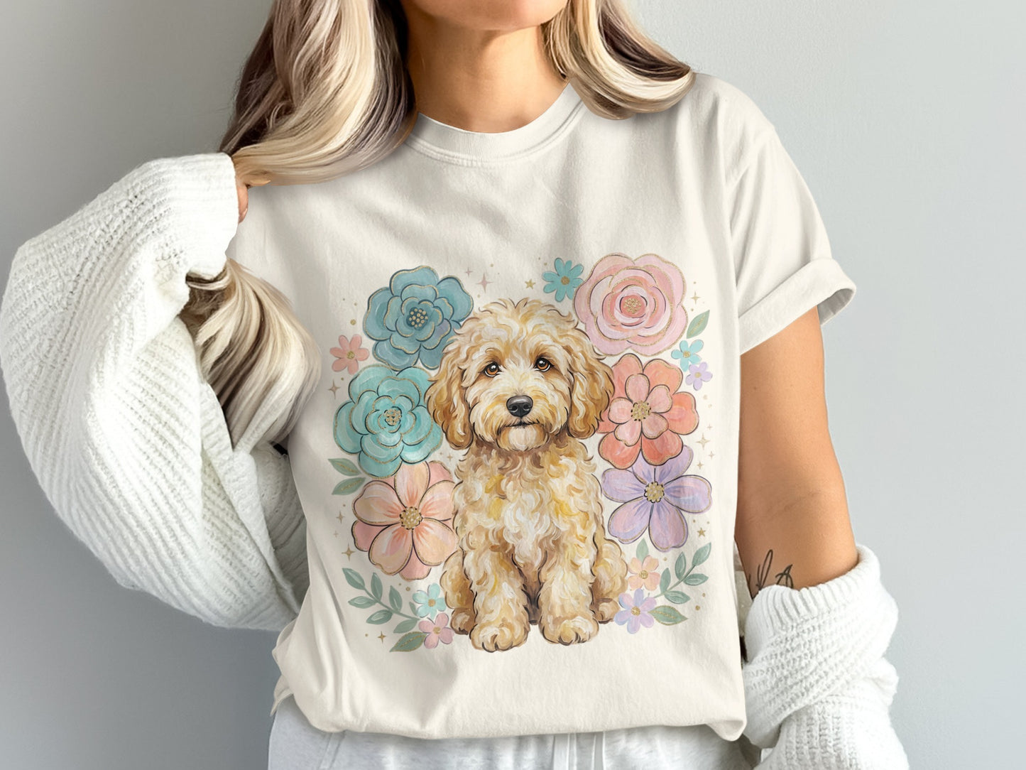 Cream t-shirt with a watercolor-style golden doodle surrounded by pastel flowers.