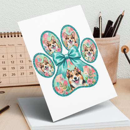Card with four corgi puppies inside a paw print with a bow.