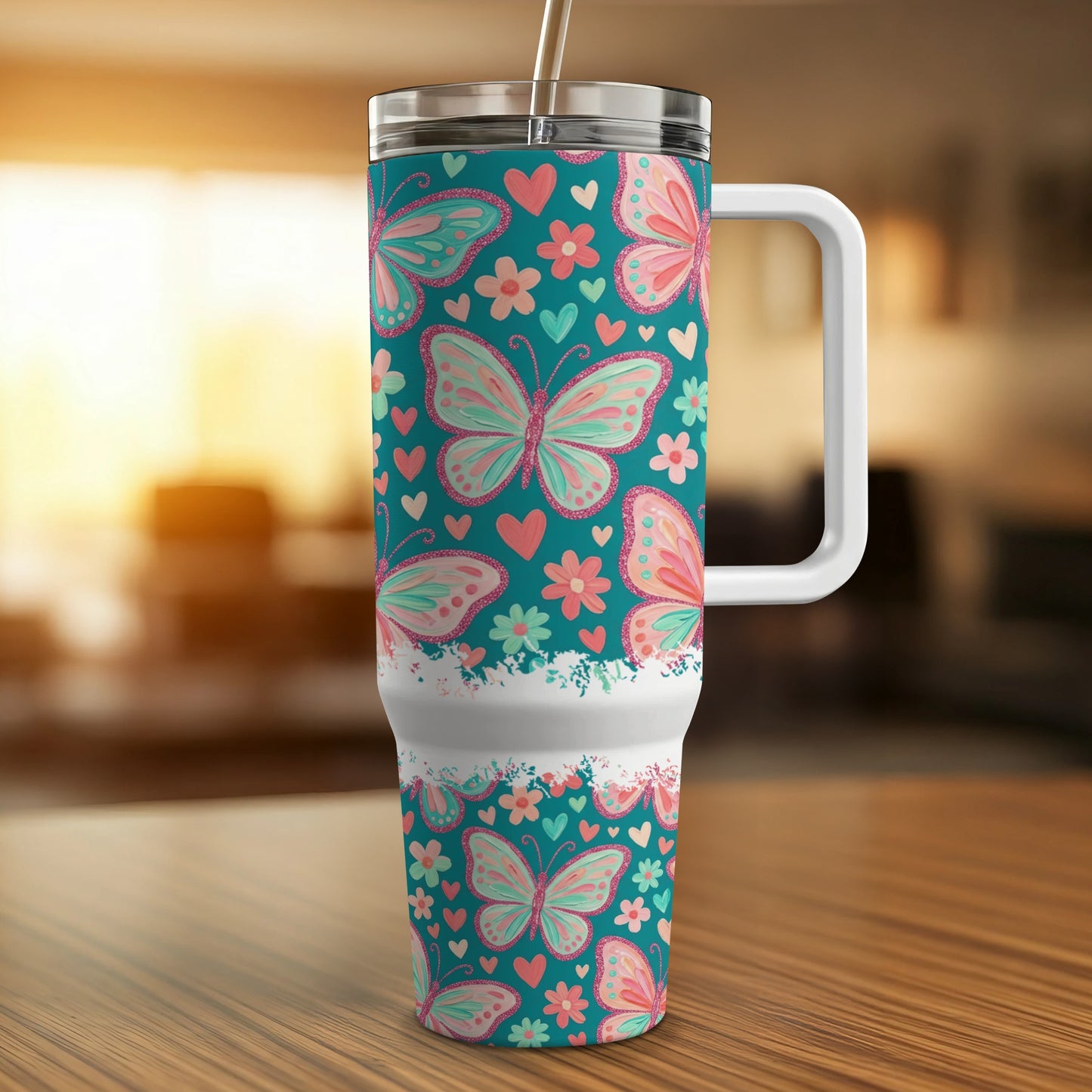 Teal tumbler with pink butterfly and heart pattern, white handle.
