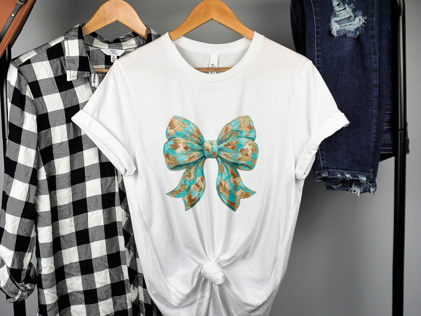 White t-shirt with a blue and gold patterned bow graphic.