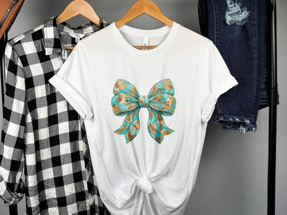 White t-shirt with a blue and gold patterned bow graphic.