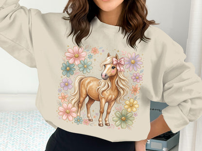 Light brown pony with pink bow, surrounded by pastel flowers, on a cream sweatshirt.
