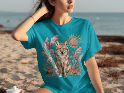 Teal t-shirt with coyote, cactus, and sun graphic on beach.