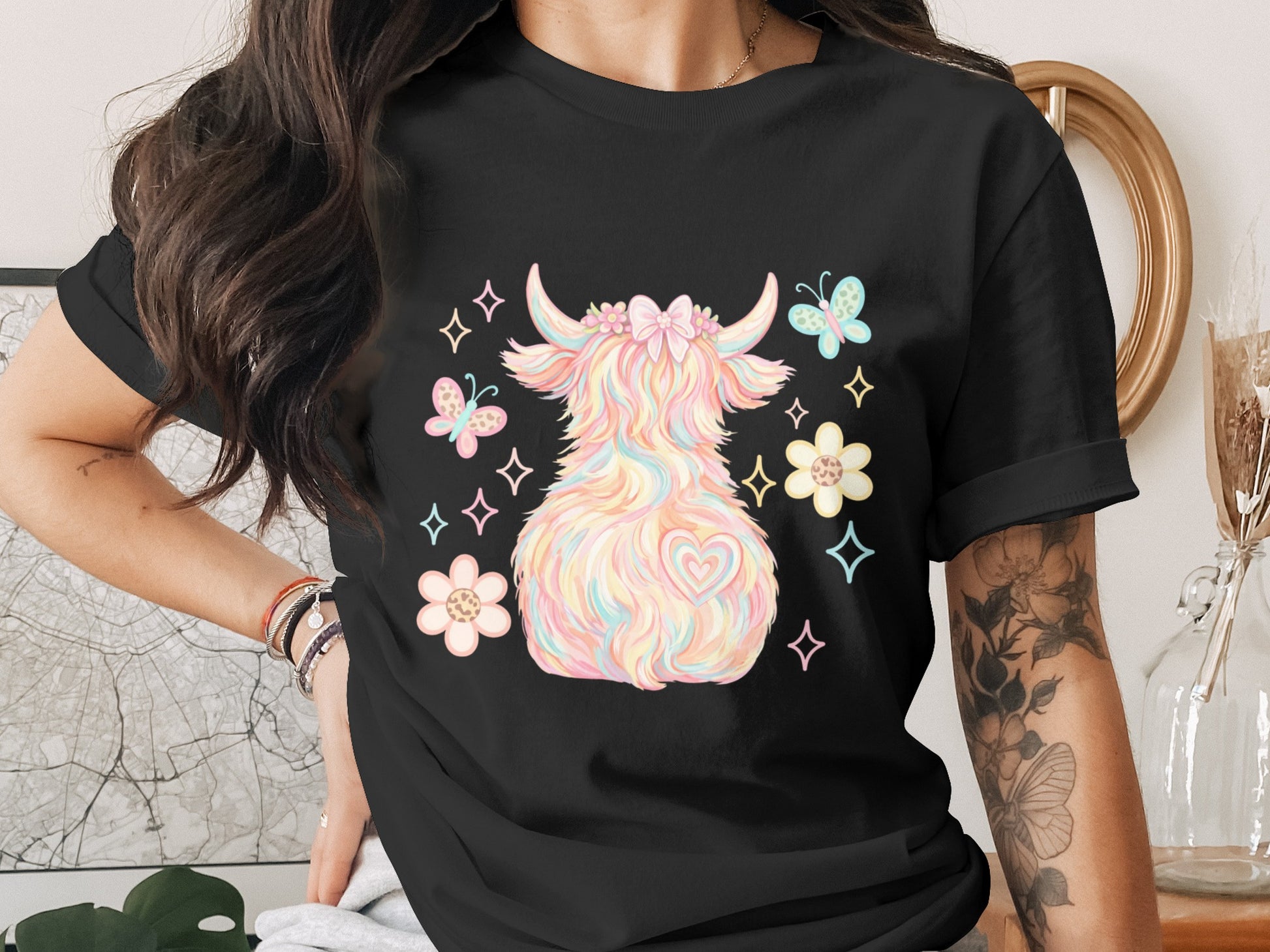 Black t-shirt with fluffy pastel highland cow wearing floral crown and butterflies.