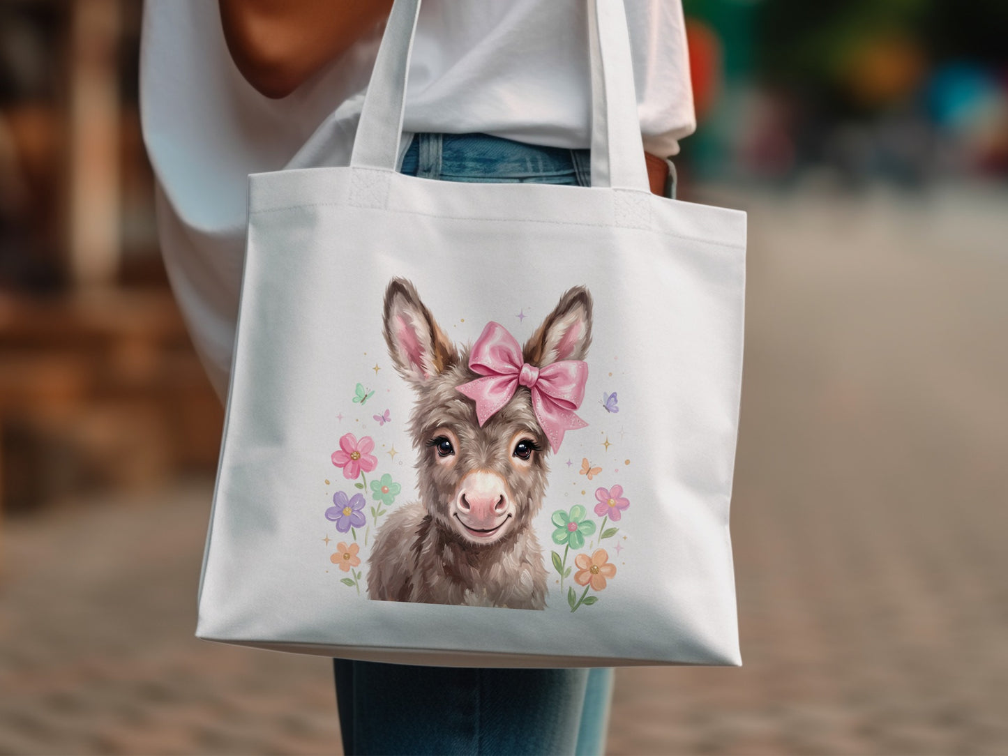 White tote bag featuring a cute donkey wearing a pink bow and surrounded by flowers.