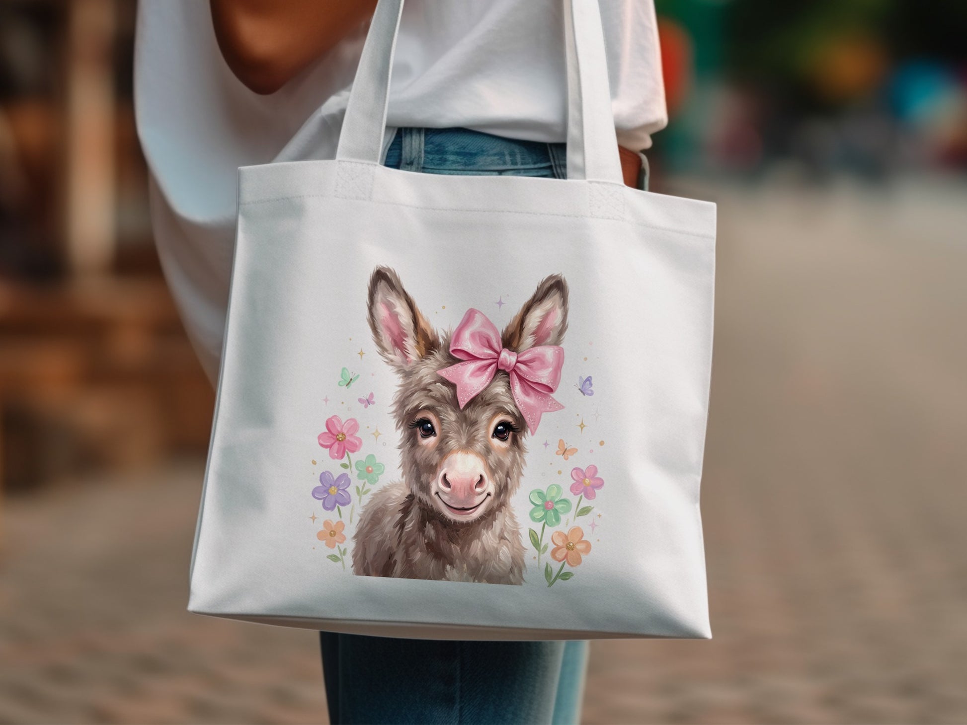 White tote bag featuring a cute donkey wearing a pink bow and surrounded by flowers.