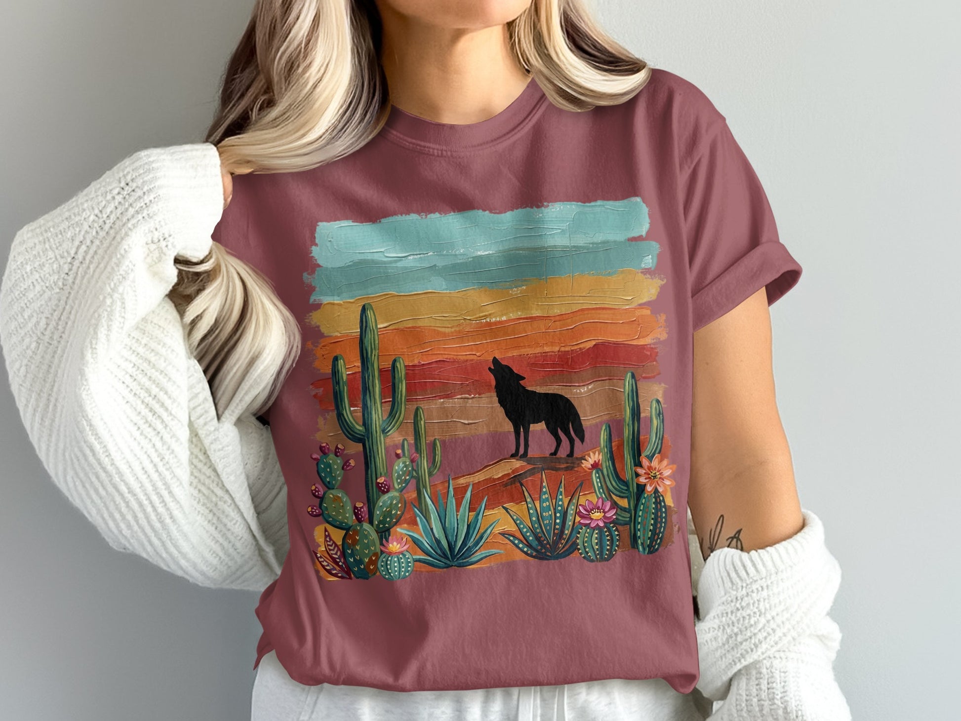 Wolf howling at sunset over cactus landscape on maroon t-shirt.
