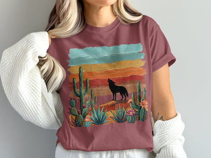 Wolf howling at sunset over cactus landscape on maroon t-shirt.