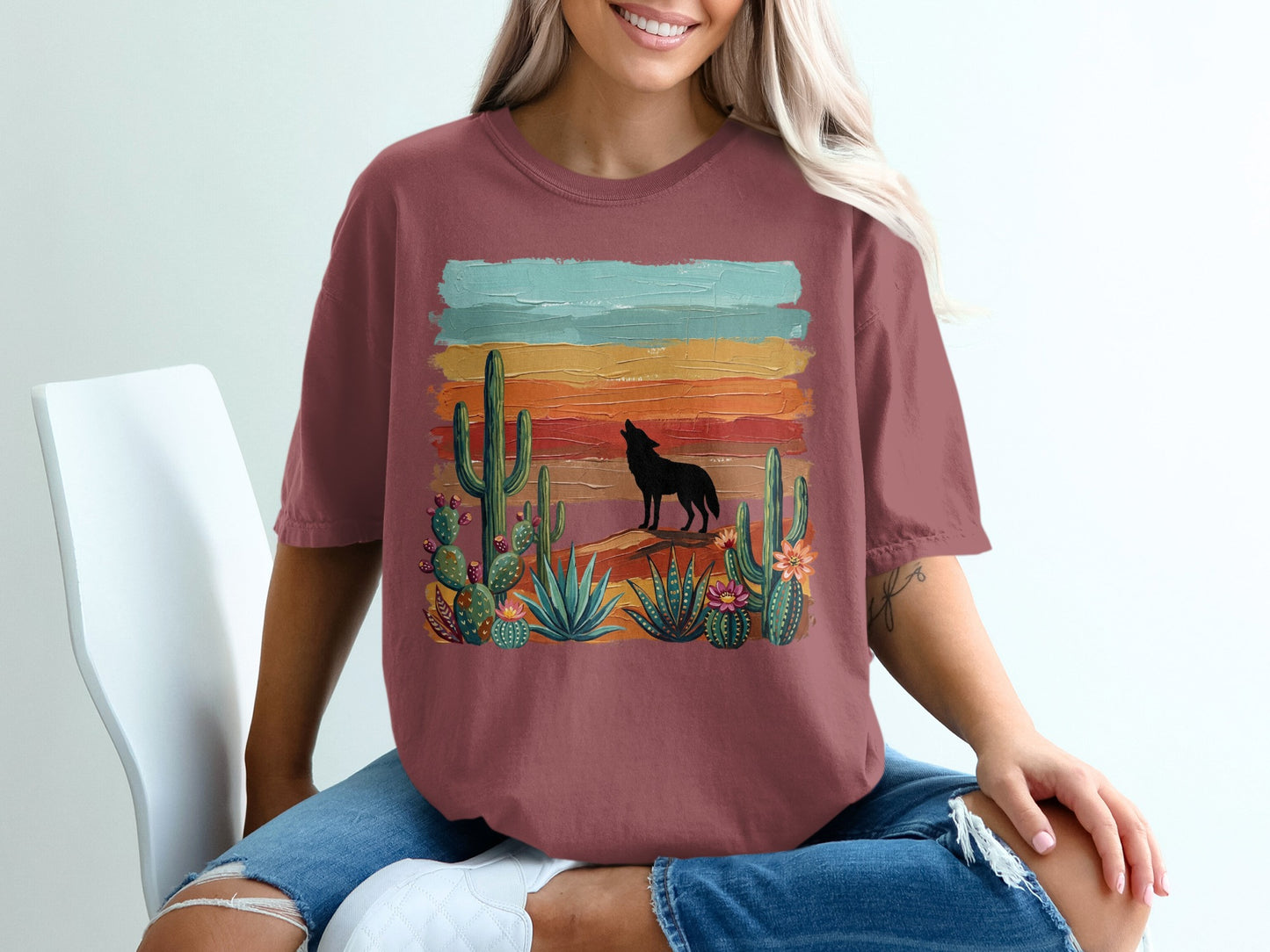 T-shirt graphic with a wolf silhouette howling at a sunset over desert cacti.