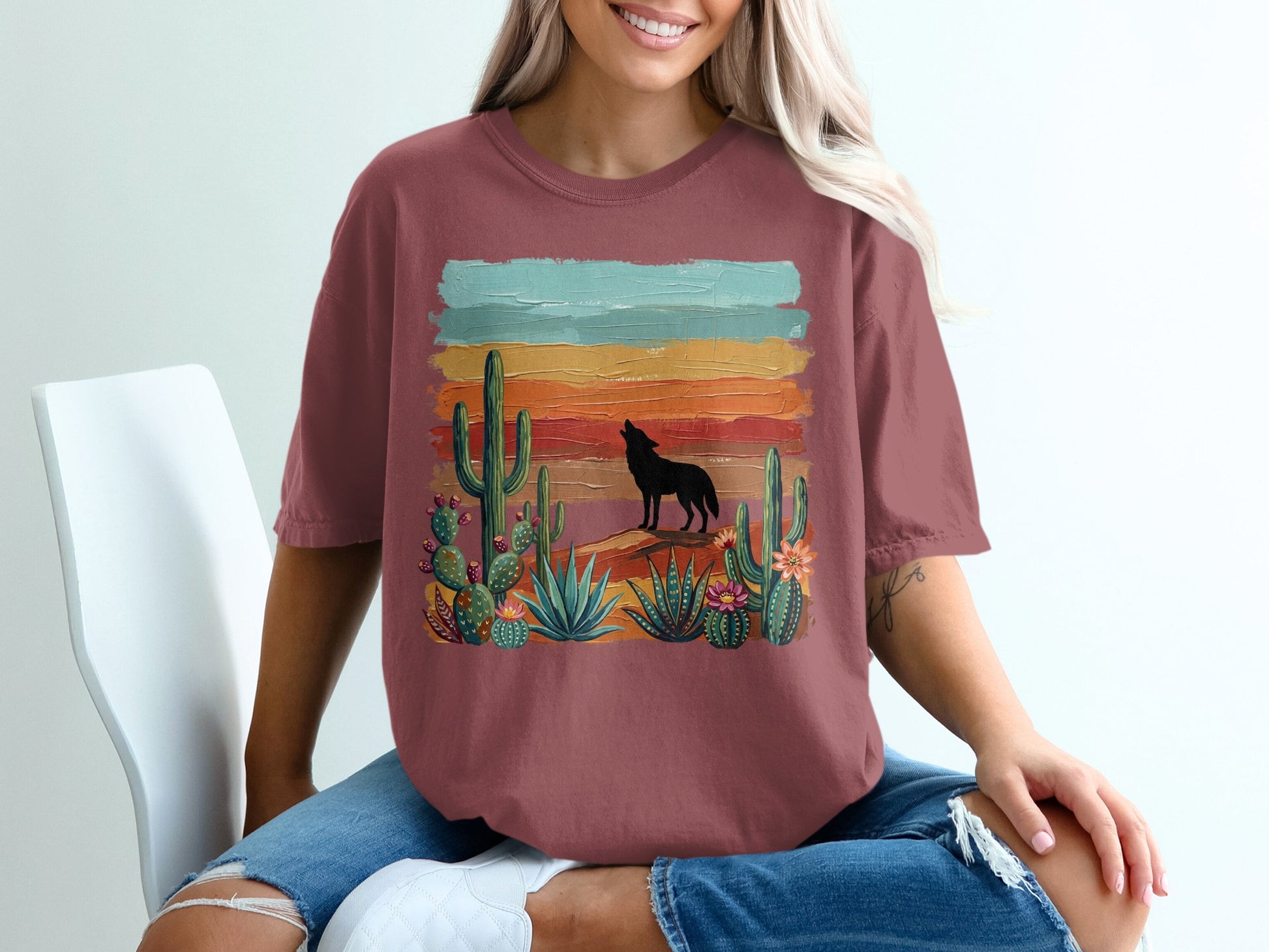 T-shirt graphic with a wolf silhouette howling at a sunset over desert cacti.