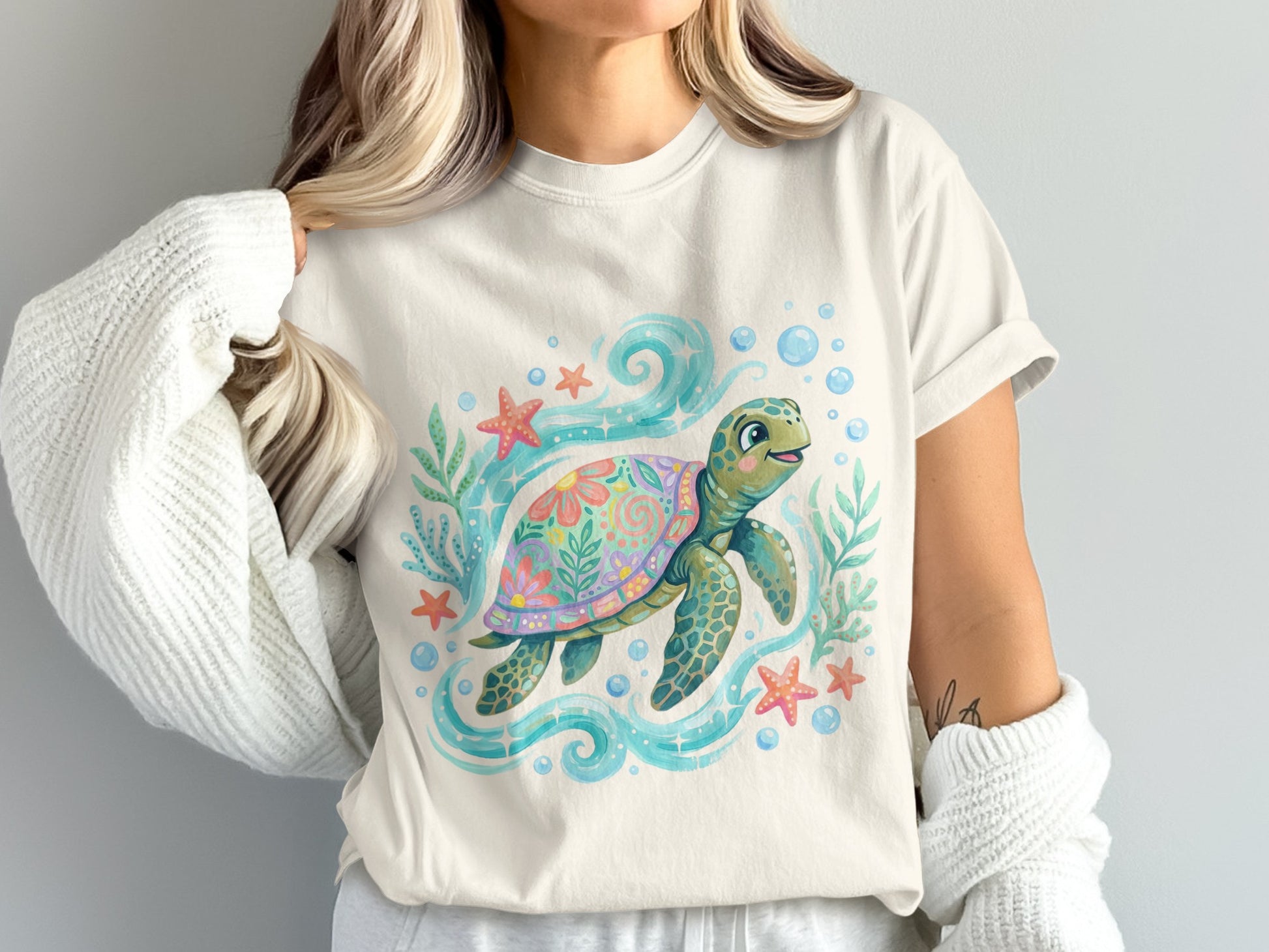 Cream t-shirt with a whimsical sea turtle illustration surrounded by starfish and bubbles.