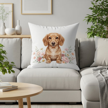 Dachshund puppy sitting on a white pillow with pink flowers.