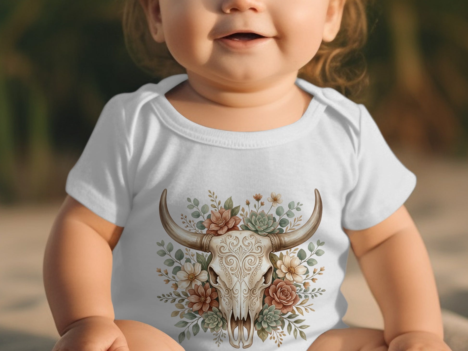 Baby in white onesie with floral bull skull graphic.