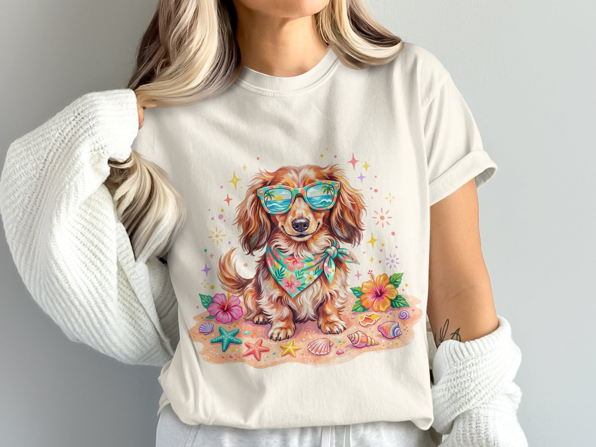 Dachshund wearing sunglasses and bandana sitting on a beach.