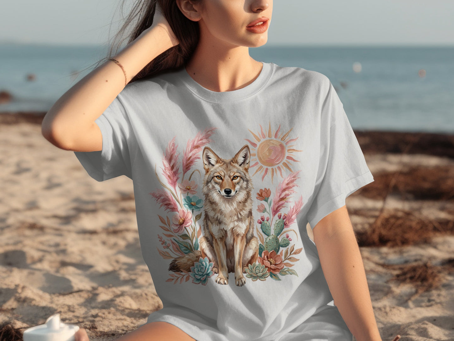 T-shirt with a coyote, cactus, sun, and floral design on a beach.