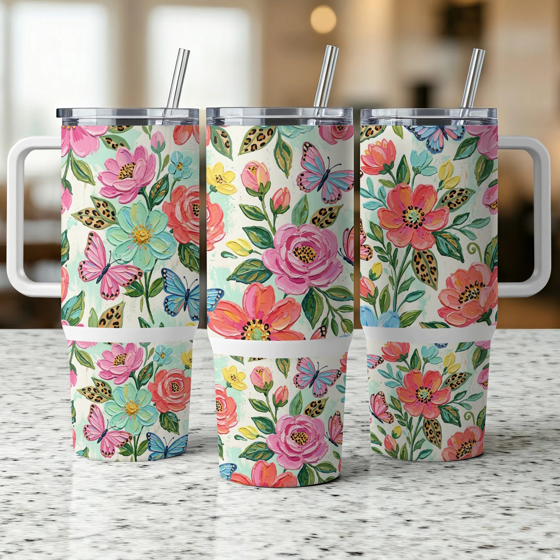 Three floral print tumblers with butterfly designs and handles.