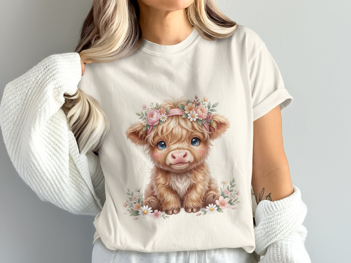 Fluffy Highland cow calf wearing a floral crown, on a light t-shirt.