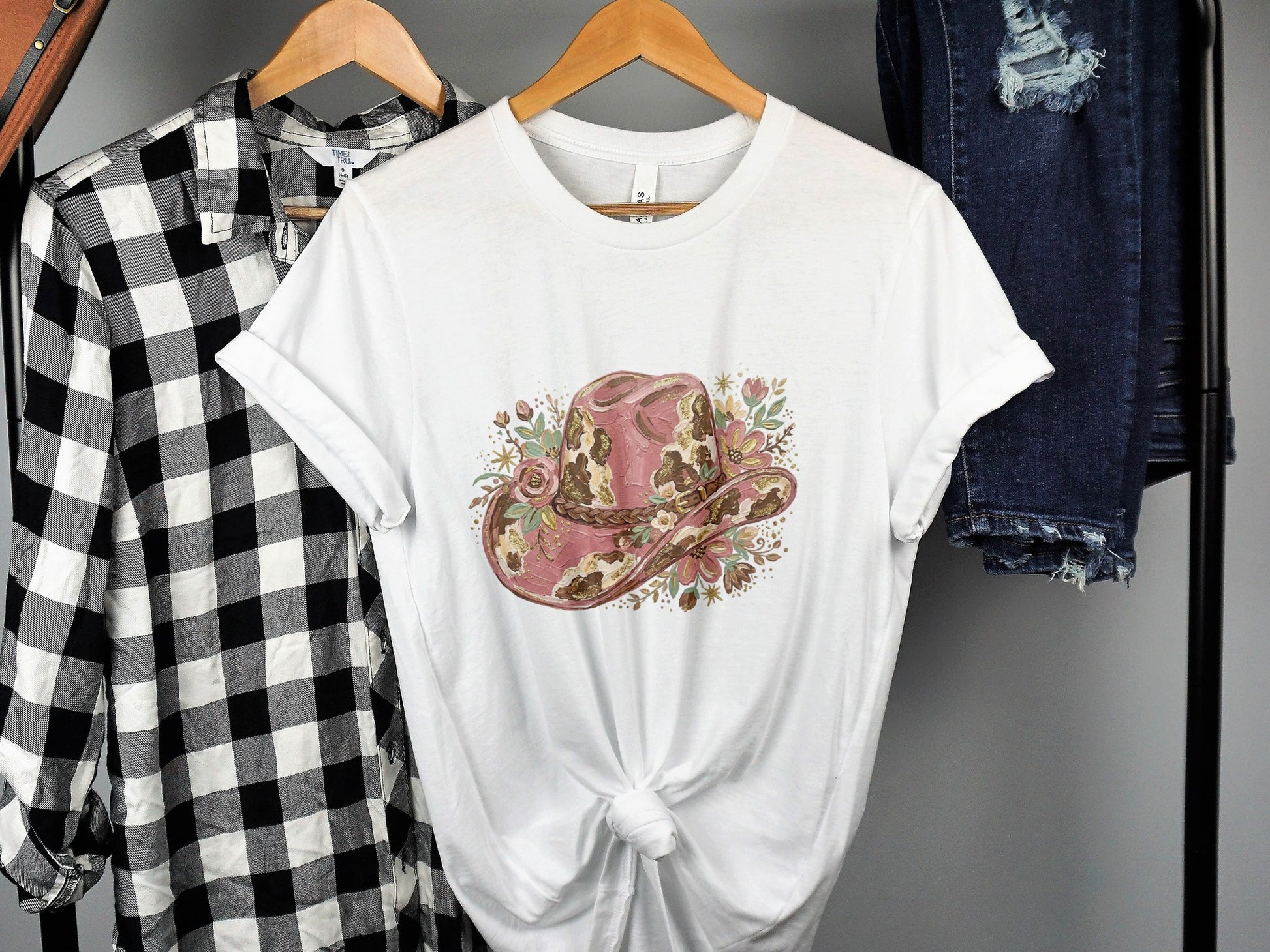 White t-shirt featuring a distressed pink cowboy hat with floral accents.