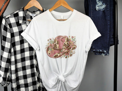 White t-shirt featuring a distressed pink cowboy hat with floral accents.