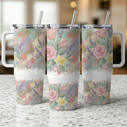 Three floral patterned tumblers with handles and straws on a speckled countertop.