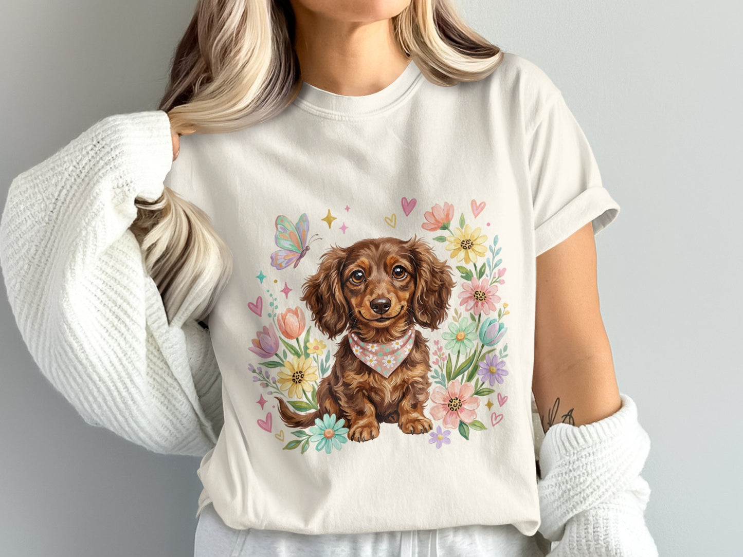 Cream t-shirt with dachshund illustration surrounded by flowers and butterflies.