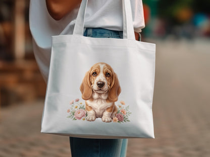 White tote bag with a watercolor painting of a basset hound puppy surrounded by flowers.