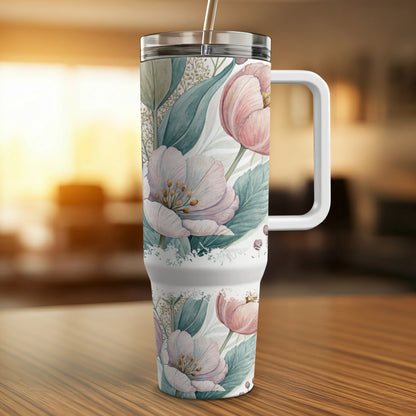 White tumbler with pink floral design and handle.