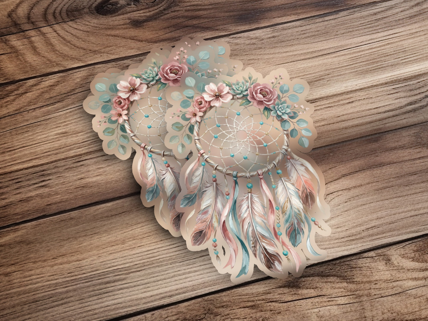 Two pastel floral dreamcatchers with feathers on wood background.