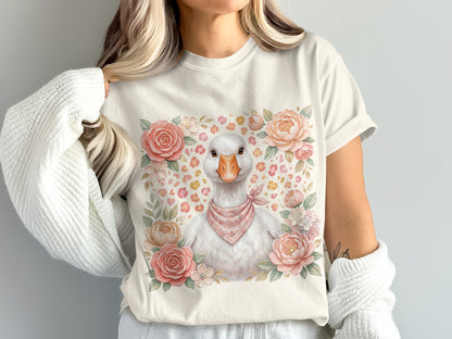 White goose wearing a pink bandana surrounded by flowers on a light t-shirt.