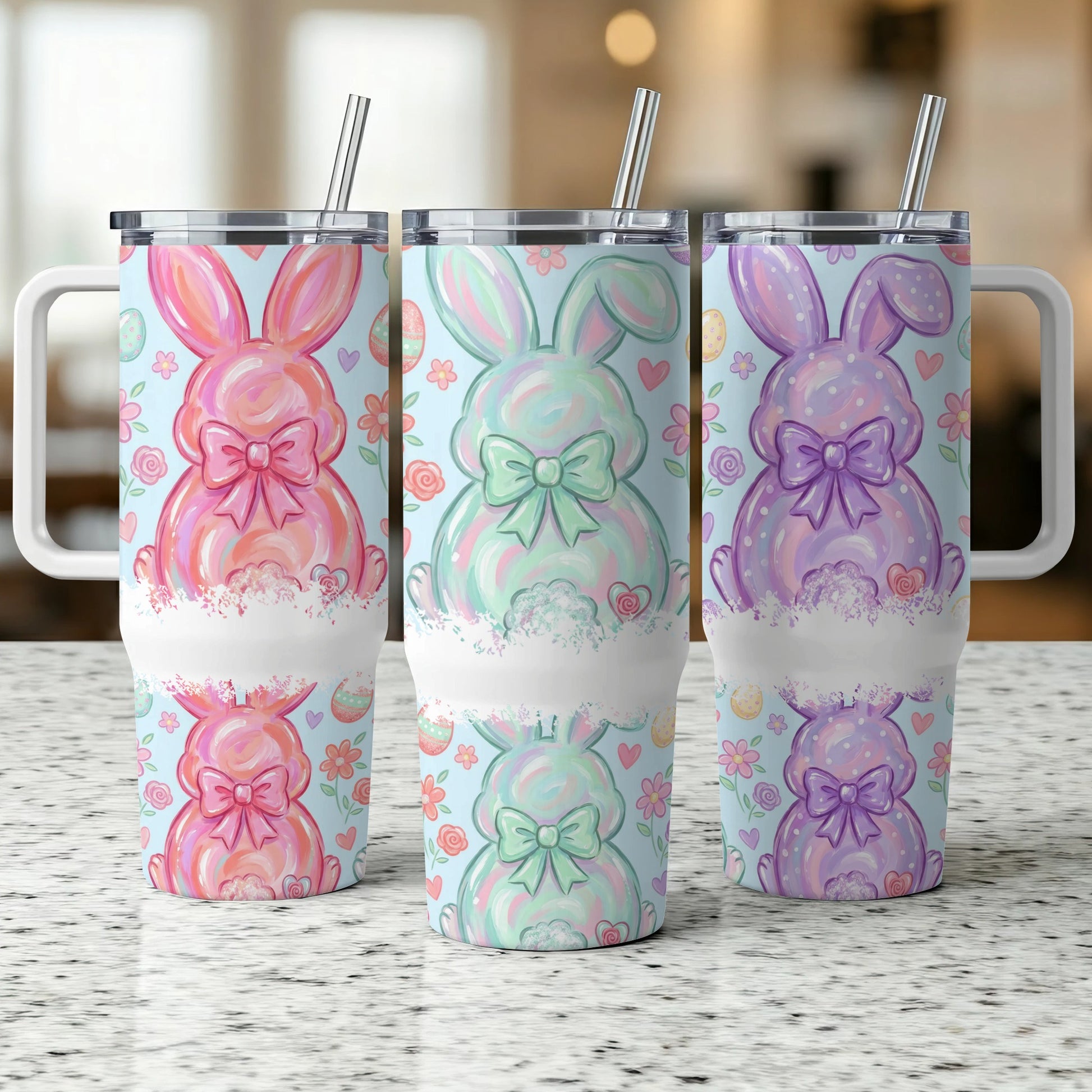 Three Easter bunny tumblers with floral patterns and bows on a speckled countertop.
