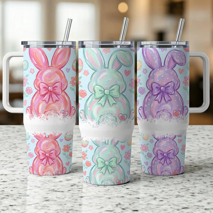 Three Easter bunny tumblers with floral patterns and bows on a speckled countertop.