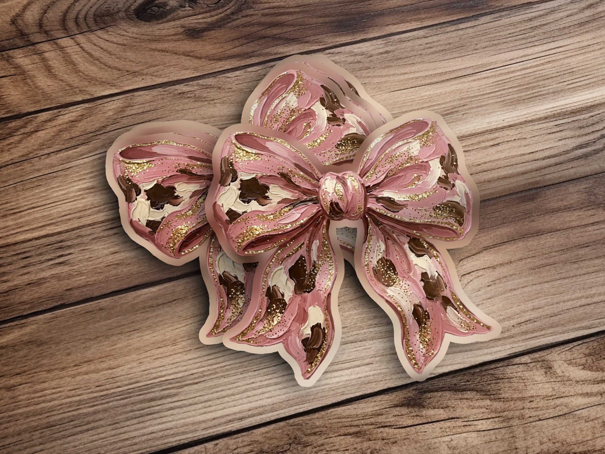 Pink bow with gold glitter accents on a wooden background.